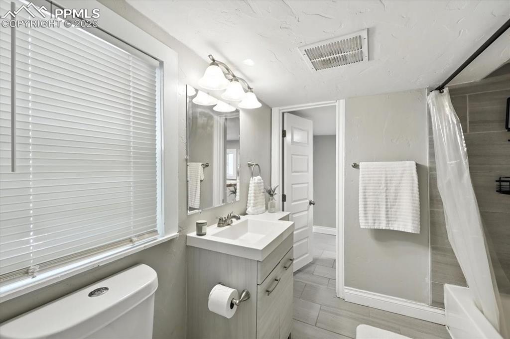 Image 17 of 36: Bathroom featuring vanity, shower / bath combo with shower curtain, and a t