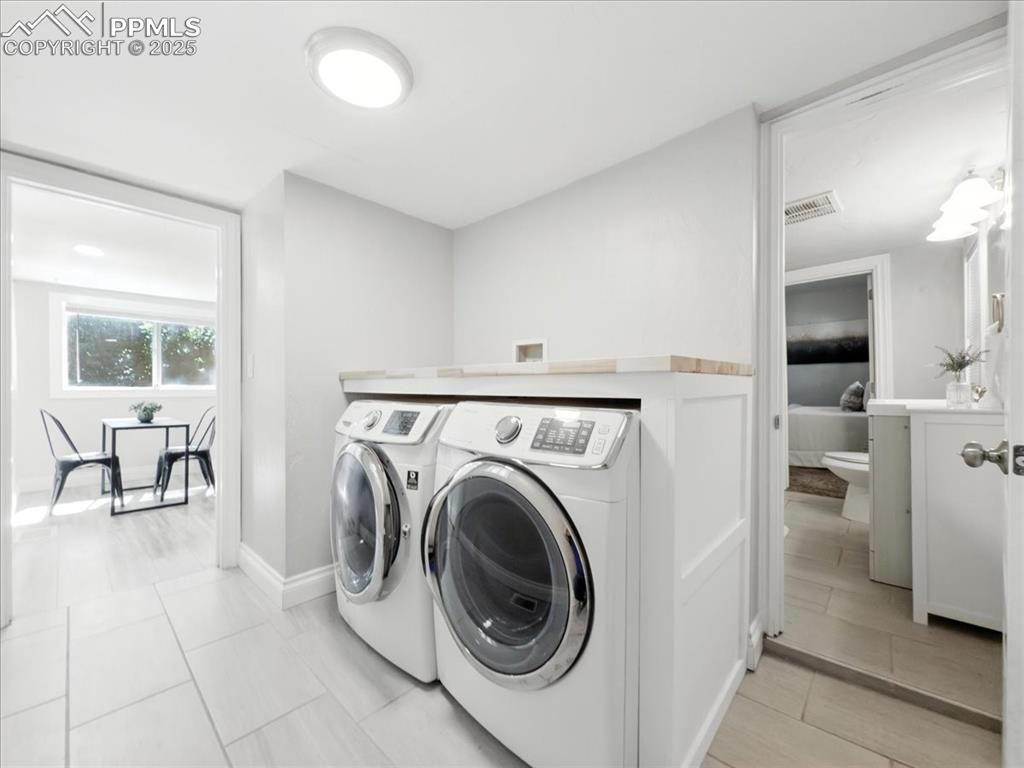 Image 20 of 36: Laundry room featuring separate washer and dryer and light tile patterned f