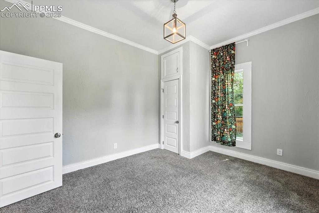 Image 22 of 36: Unfurnished room featuring dark carpet and ornamental molding