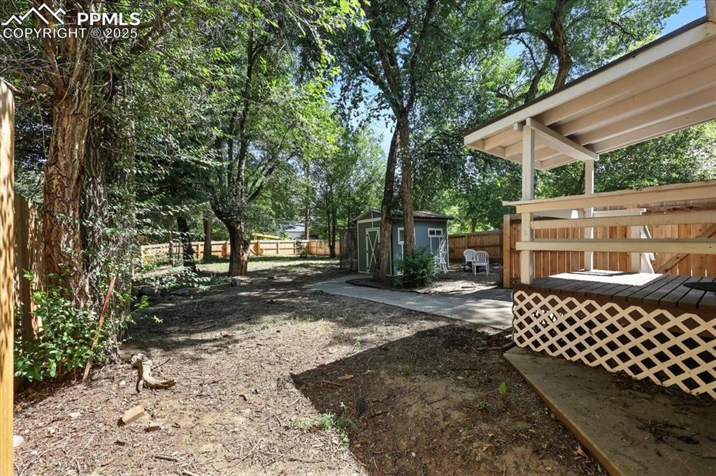 Image 26 of 36: Fenced backyard with a storage shed, a deck, and a patio