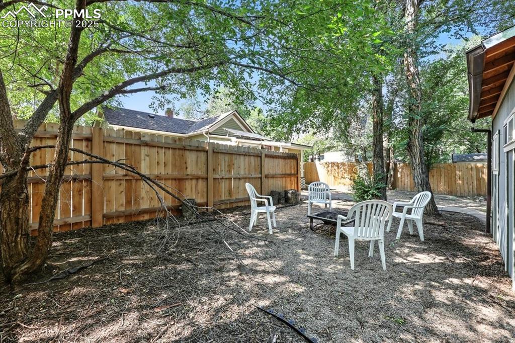 Image 33 of 36: Fenced backyard featuring an outdoor fire pit