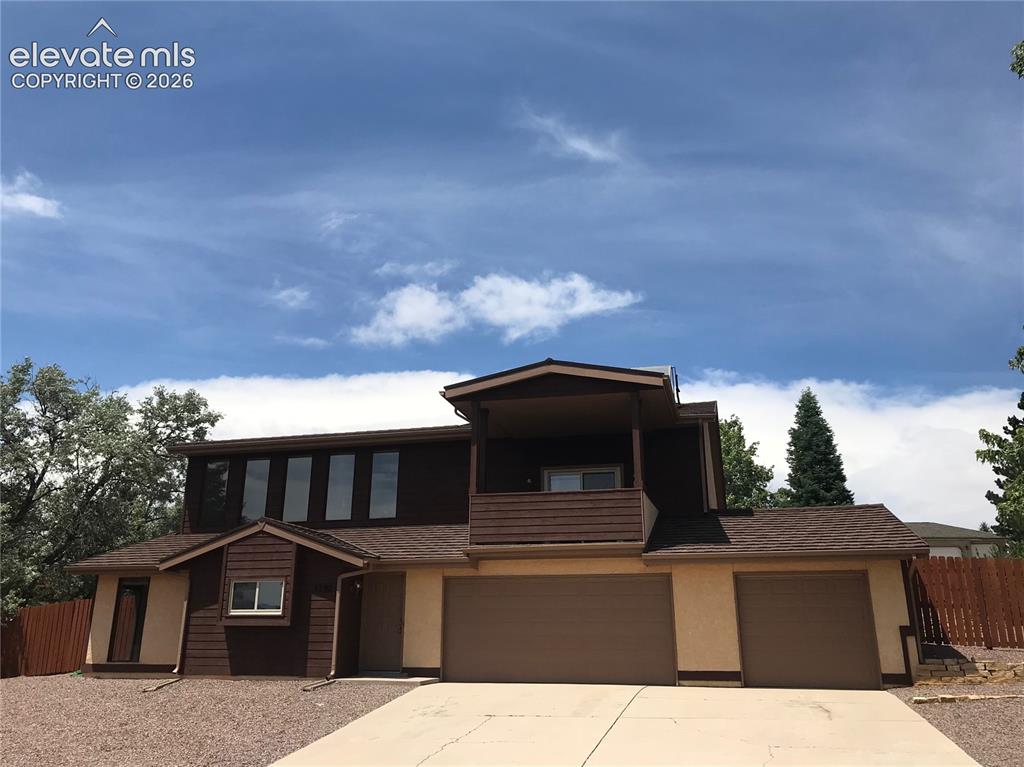 Caption: Two-story exterior with a multi-car garage, upper-level balcony, shingle roofing, and a combination 