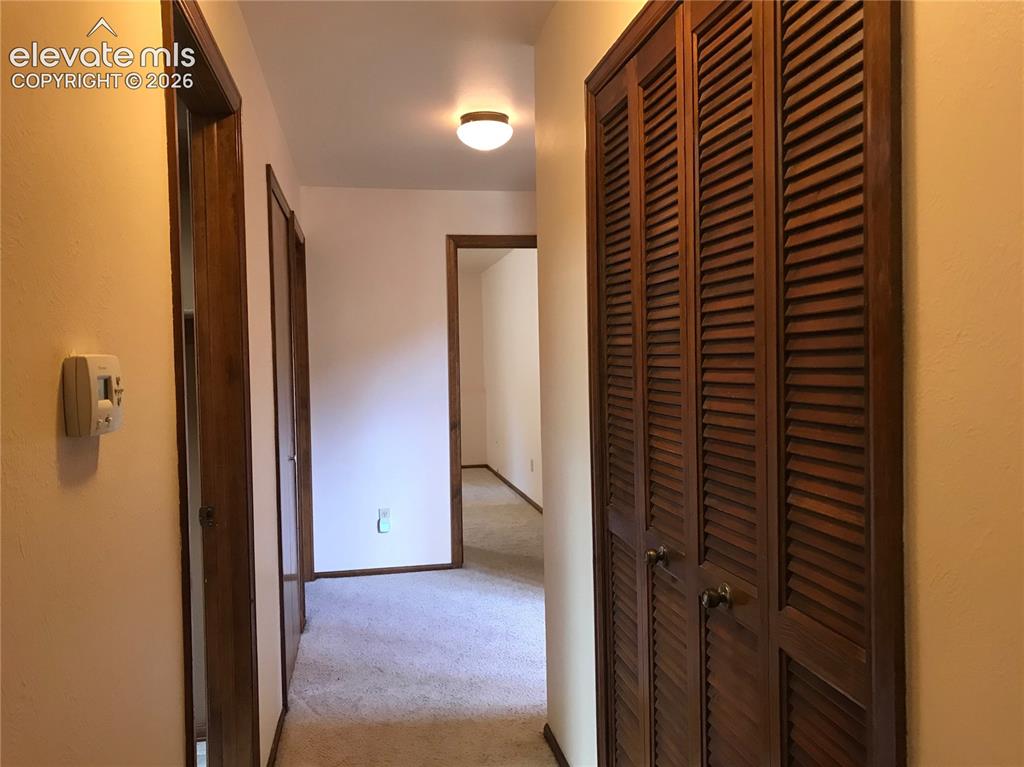 Image 14 of 35: Hallway featuring light-toned walls, wood-finish interior doors with trim,