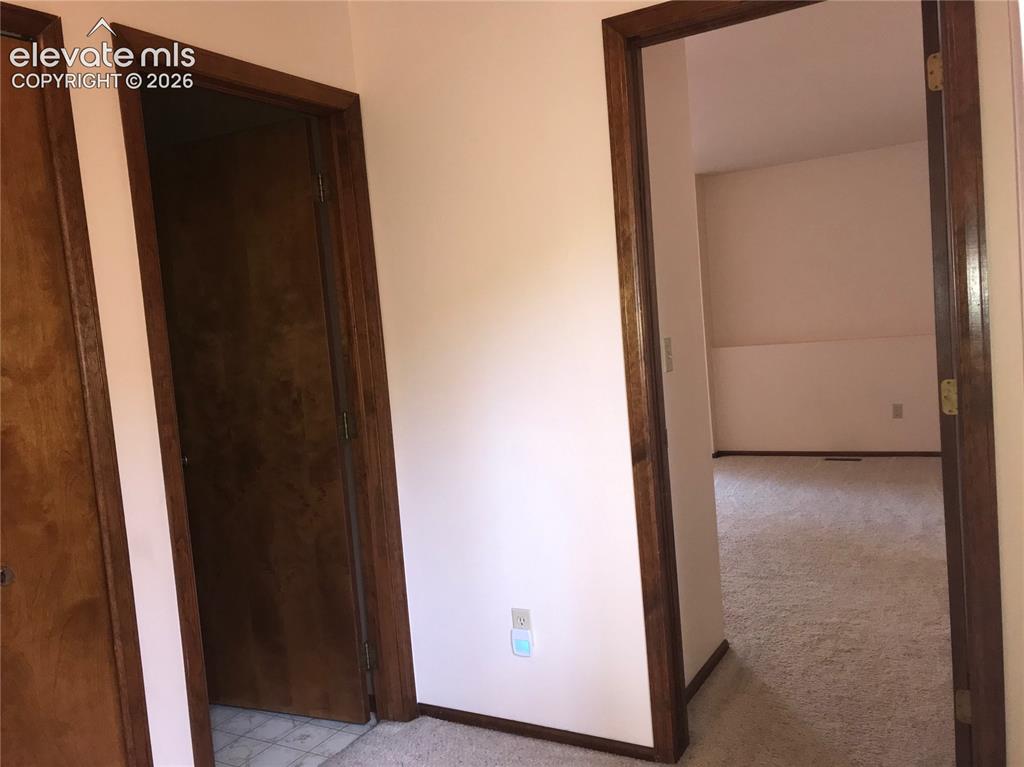 Image 16 of 35: Interior doorway with dark wood trim opening to a carpeted room