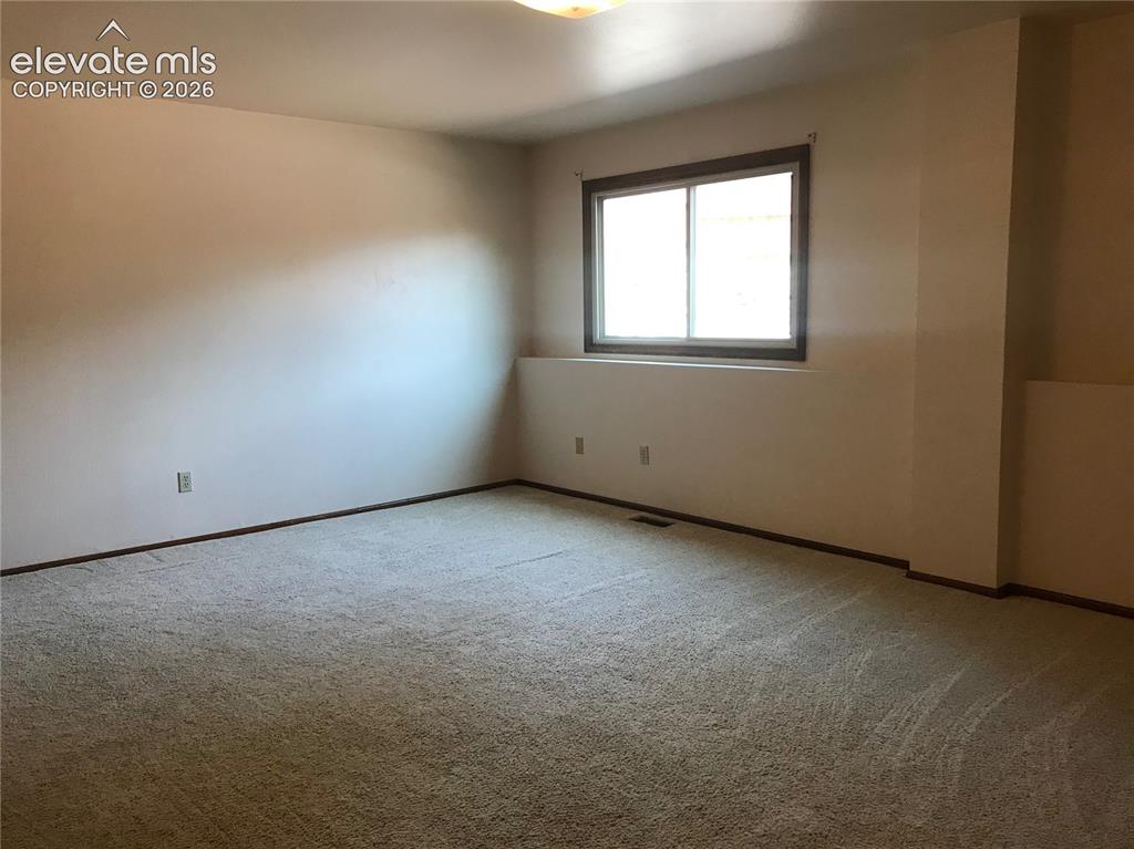 Image 17 of 35: Spacious room featuring neutral carpeting, light-colored walls, and a windo