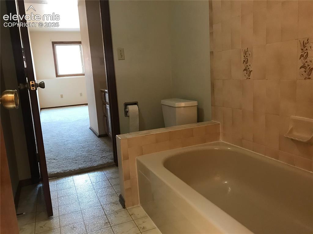 Image 18 of 35: Bathroom featuring a built-in bathtub with tiled surround, patterned wall t