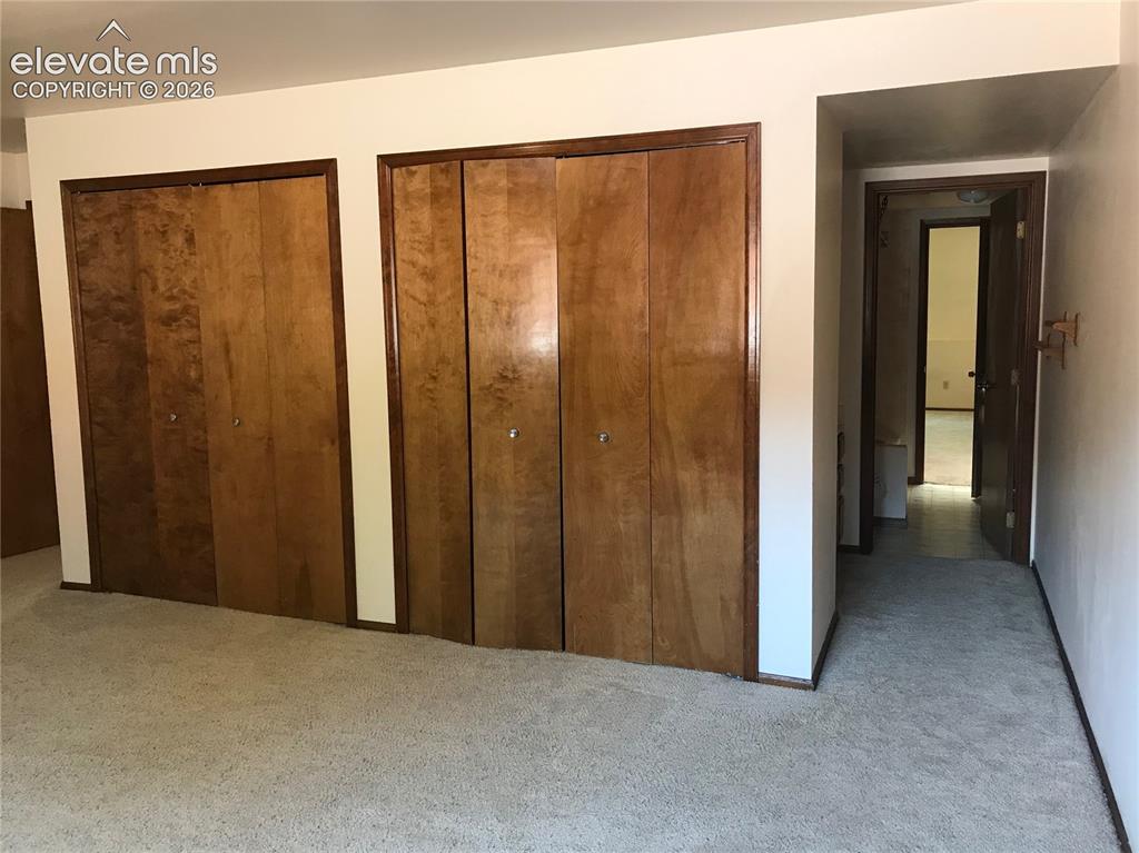 Image 21 of 35: Two large wood-finish closet doors with dark wood trim, wall-to-wall carpet