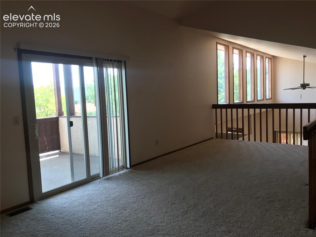 Image 25 of 35: Carpeted loft area featuring a wood railing overlooking the lower level, a 