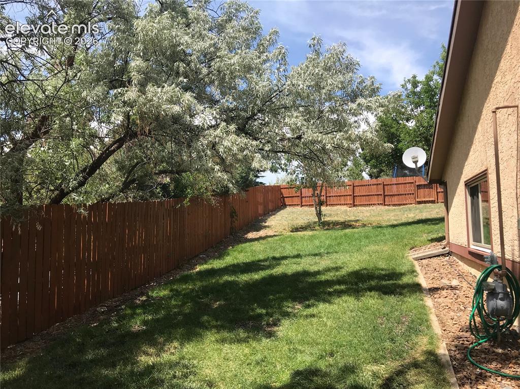 Image 31 of 35: Spacious backyard featuring a manicured lawn, a full wood privacy fence, an