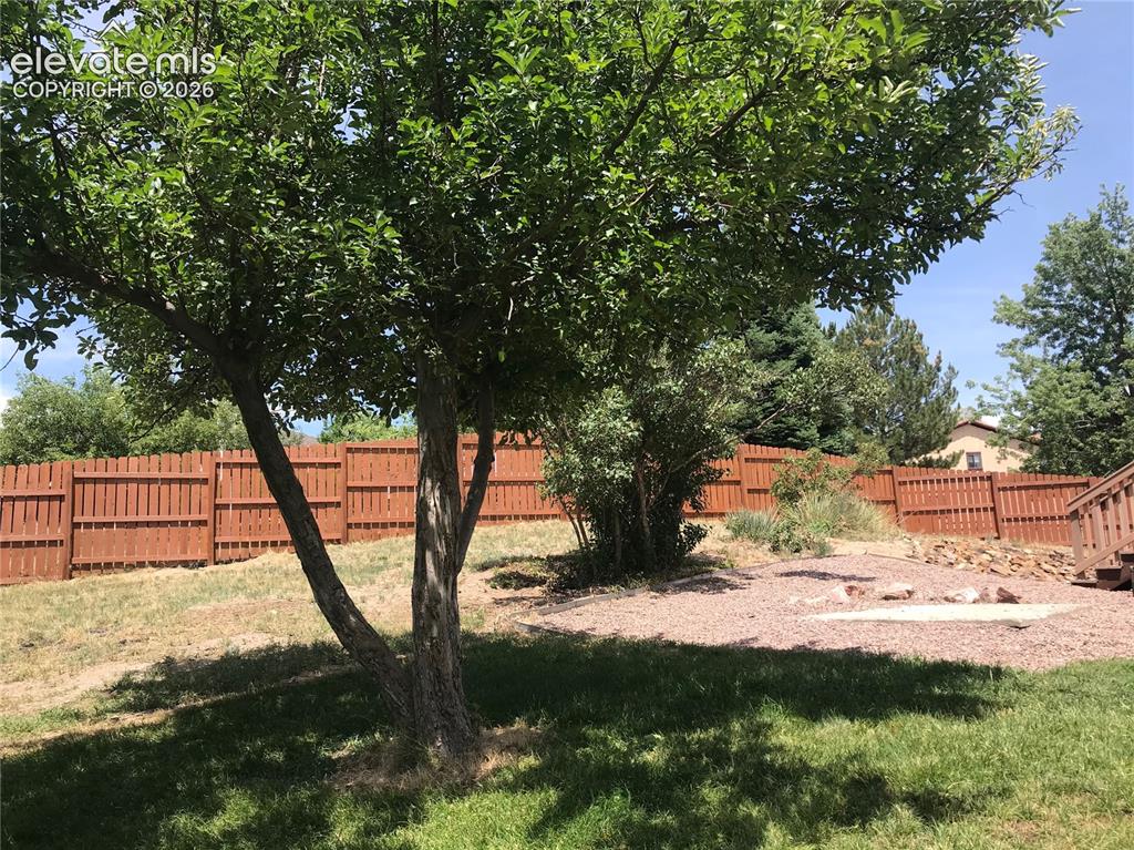 Image 32 of 35: Expansive backyard featuring mature trees, a manicured lawn, a privacy fenc