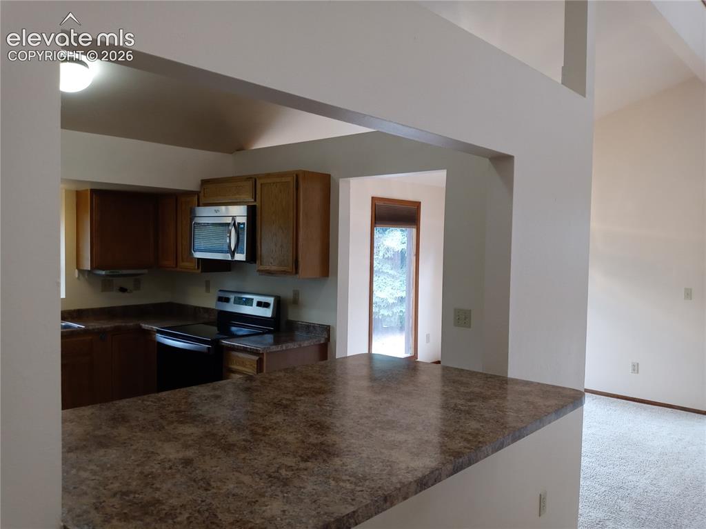 Image 6 of 35: Kitchen featuring a breakfast bar with a patterned countertop, wood cabinet
