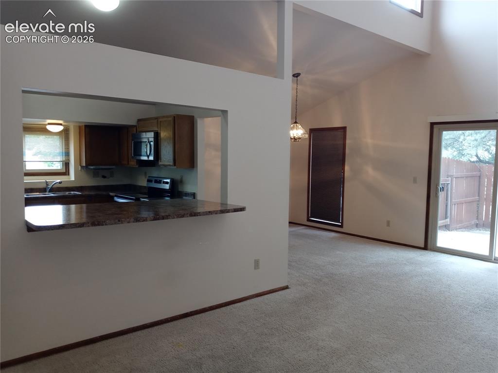 Image 7 of 35: Kitchen pass-through with a breakfast bar featuring a stone-finish countert