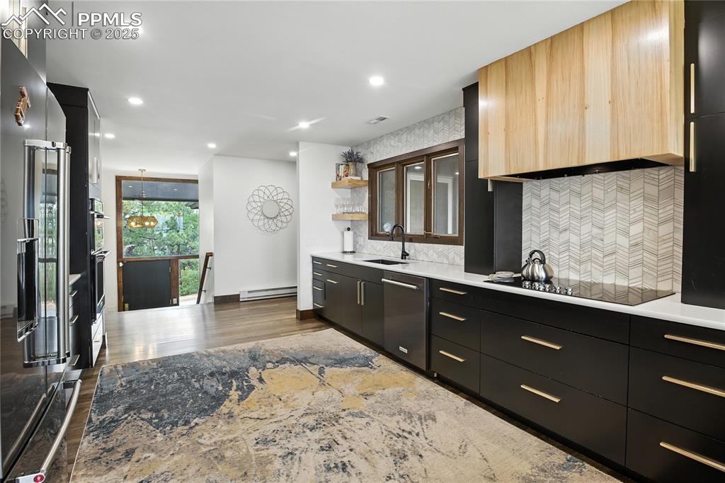 Image 10 of 50: Kitchen featuring open shelves, dark cabinetry, modern cabinets, backsplash