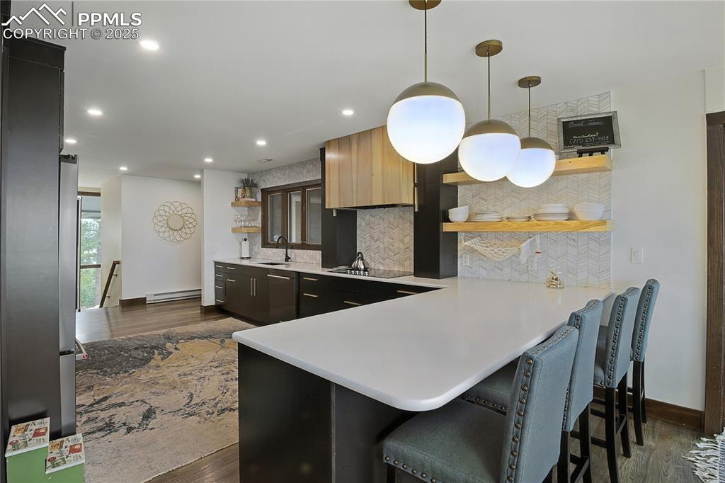 Image 16 of 50: Kitchen featuring open shelves, a peninsula, decorative backsplash, dark wo