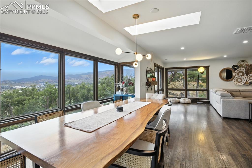Image 17 of 50: Dining area with a skylight, a mountain view, dark wood-style floors, and r