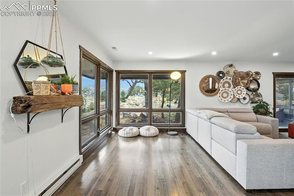 Image 19 of 50: Living room with a baseboard heating unit, wood finished floors, and recess