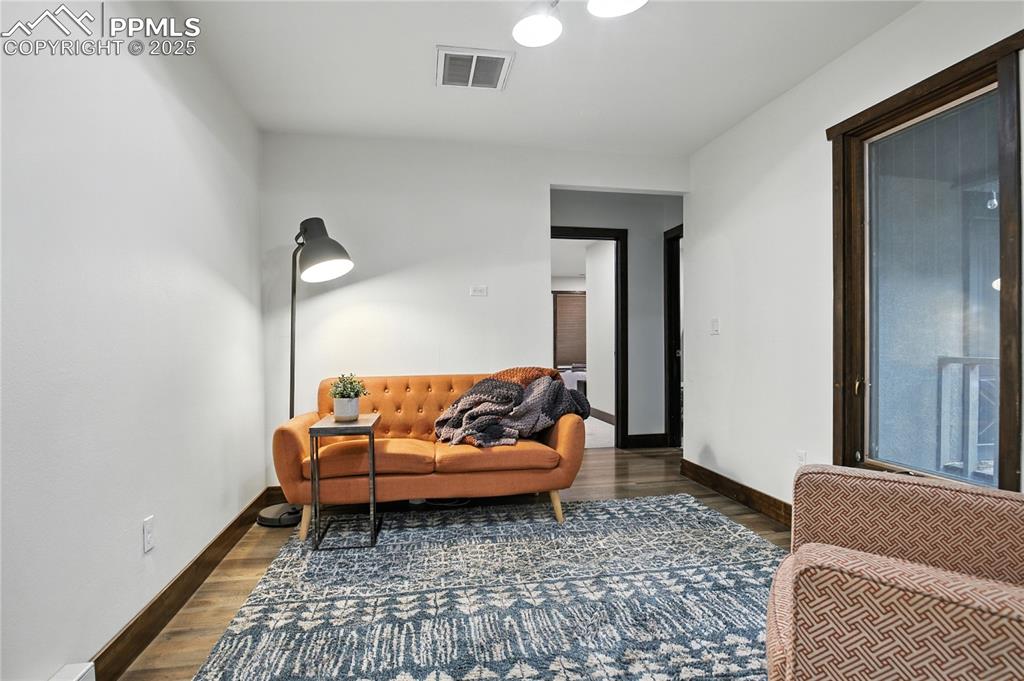 Image 39 of 50: Living area featuring dark wood-style flooring and baseboards