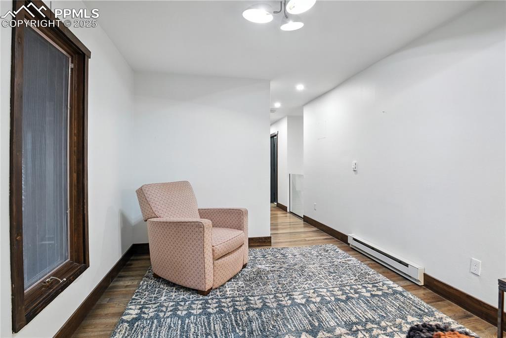 Image 46 of 50: Living area with baseboard heating, wood finished floors, and recessed ligh