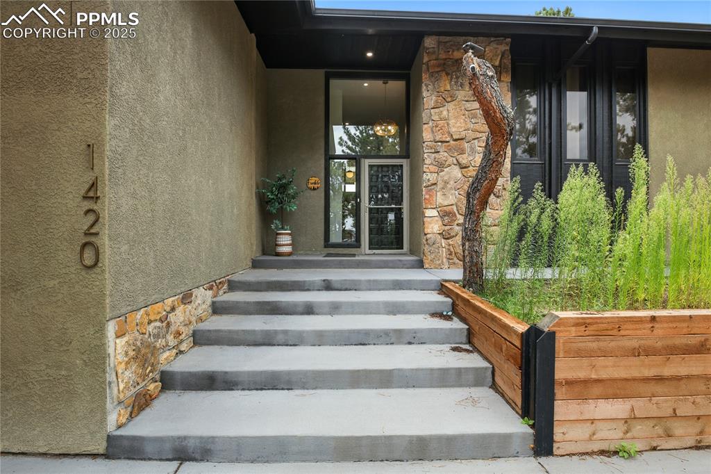 Image 6 of 50: Doorway to property with stone siding and stucco siding