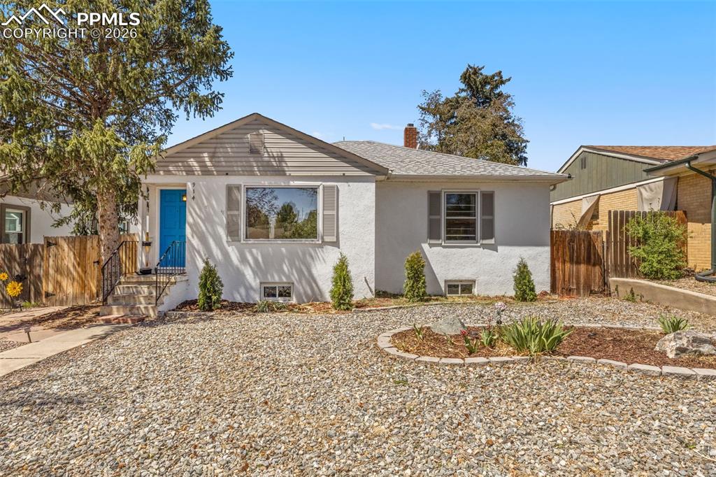 Caption: White stucco exterior with a contrasting blue front door and grey shutters