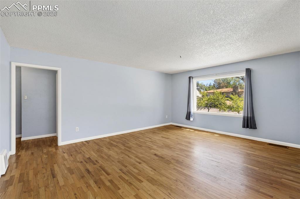 Image 13 of 50: Spacious room featuring wood-finish flooring, light blue walls, white trim,