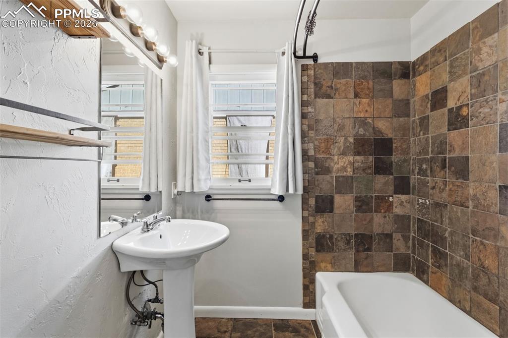 Image 26 of 50: Pedestal sink with chrome fixtures, framed mirror, and integrated vanity li