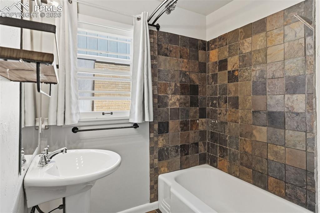 Image 27 of 50: Bathroom featuring a pedestal sink with chrome fixtures, a tiled shower sur