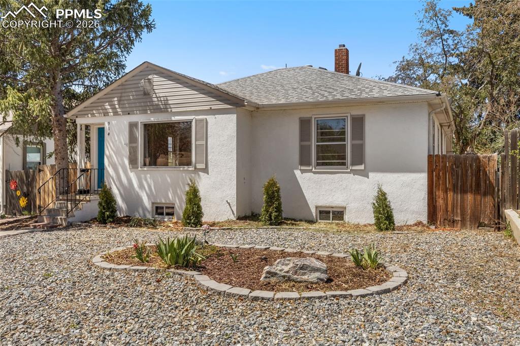 Image 3 of 50: Exterior featuring white stucco siding, a gabled roof, and a gravel front y