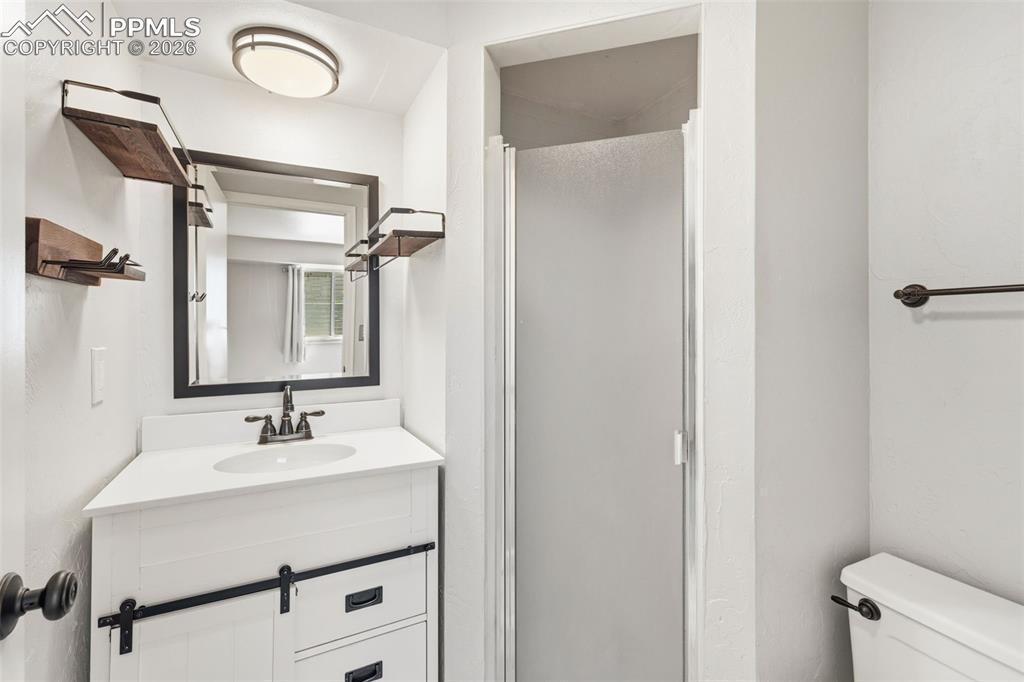 Image 43 of 50: Bathroom featuring a white vanity with an integrated sink, dark bronze hard