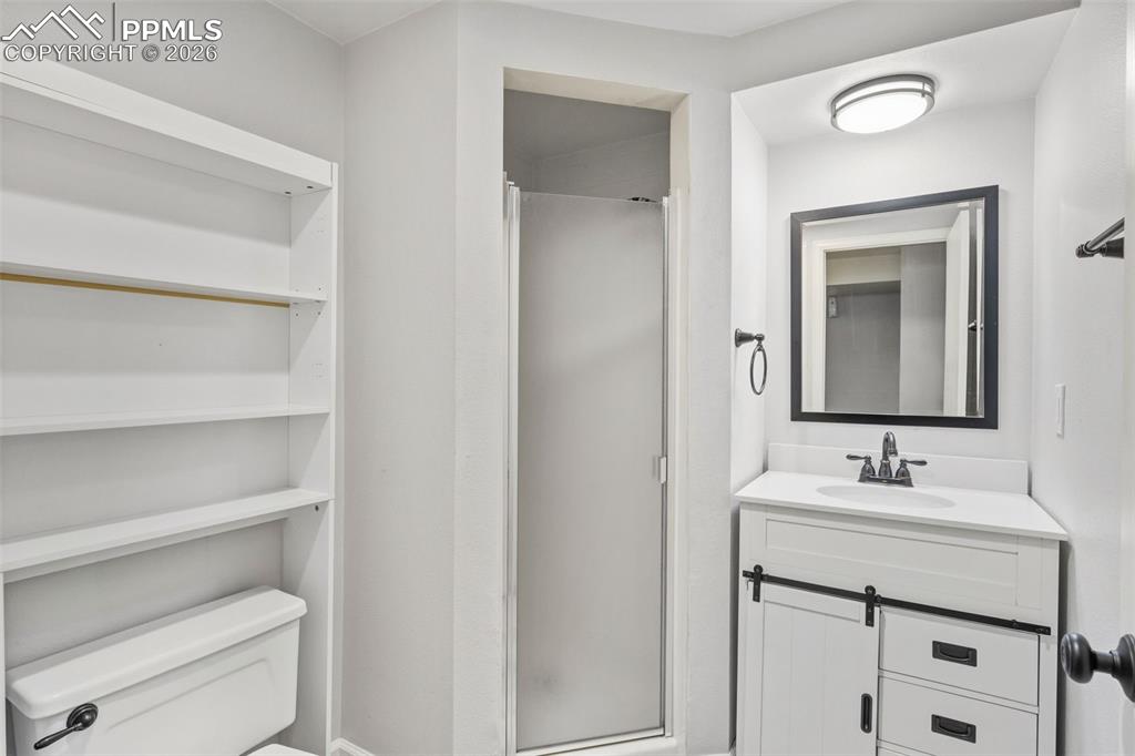 Image 44 of 50: Bathroom featuring a white vanity with a barn door-style cabinet, a rectang