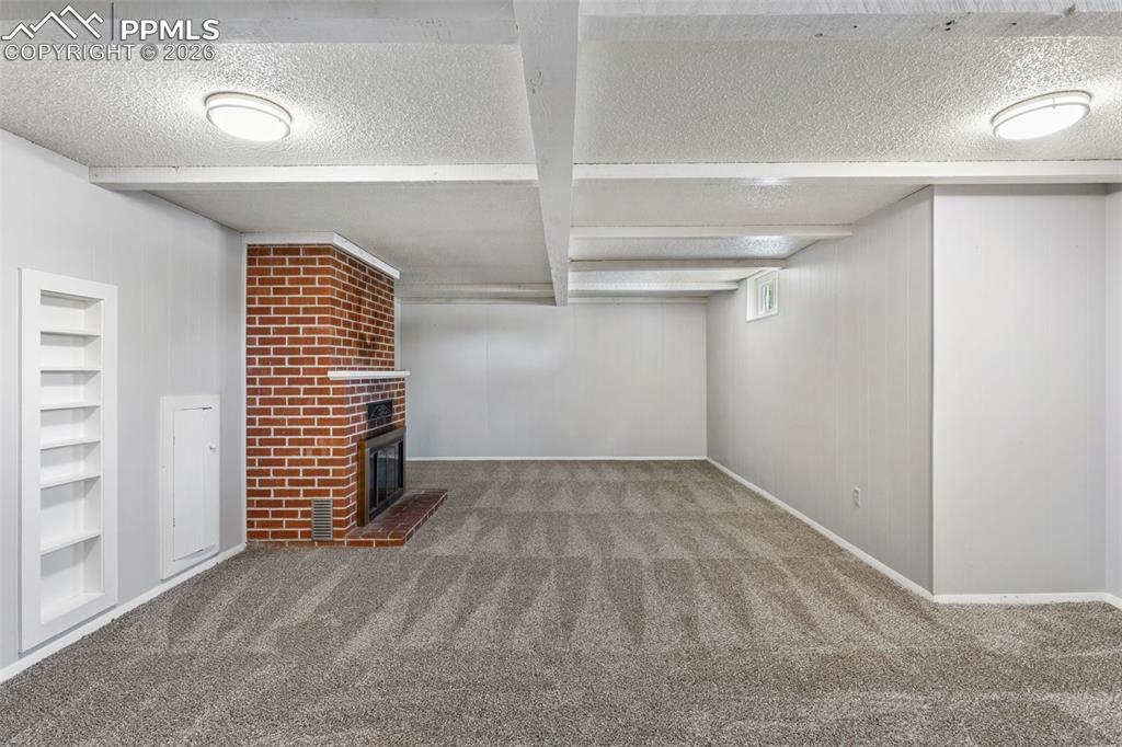 Image 45 of 50: Spacious interior featuring a brick fireplace with a wood mantle, neutral w