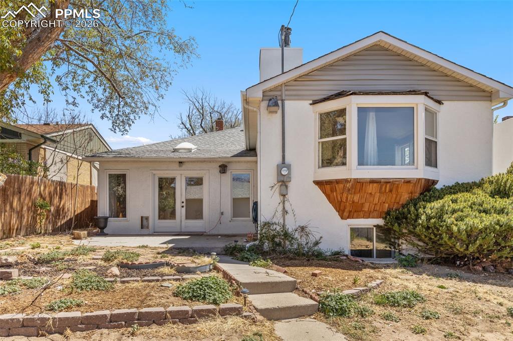 Image 47 of 50: Rear exterior featuring a concrete patio, double glass panel doors, and a s