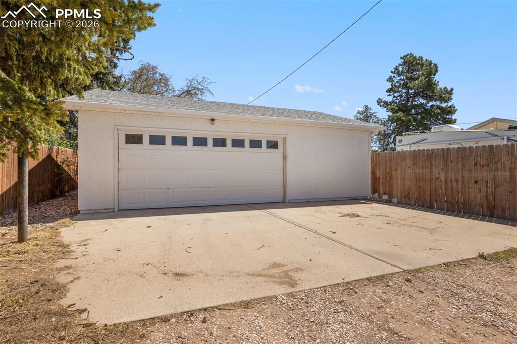 Image 48 of 50: Detached garage featuring a white overhead door with window inserts, stucco