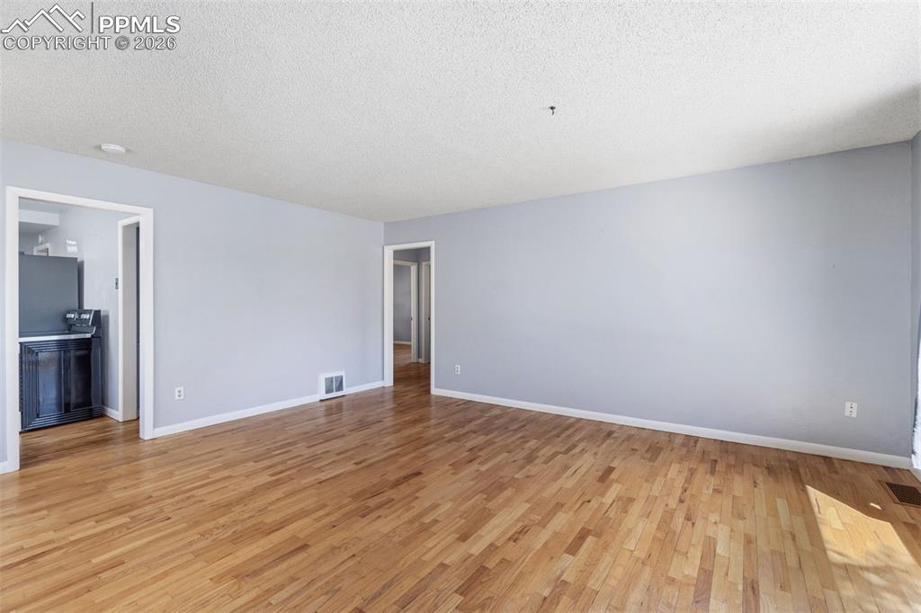 Image 5 of 50: Spacious room featuring wood-finish flooring, light-colored walls, and whit