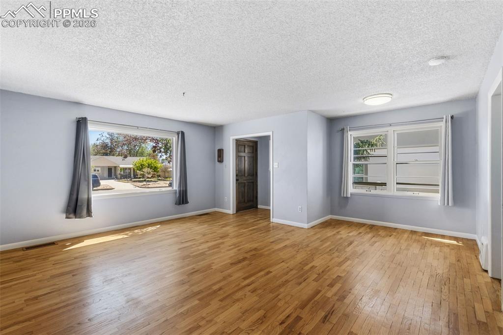 Image 7 of 50: Spacious interior with wood-finish flooring, light blue wall paint, and whi
