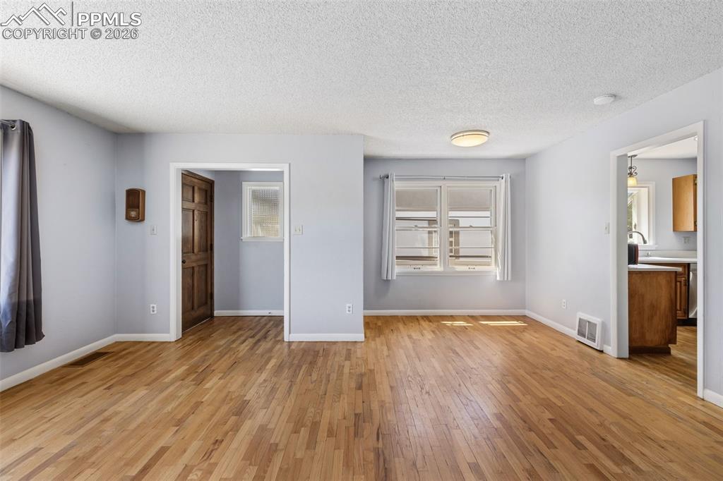 Image 9 of 50: Expansive room featuring wood-finish flooring, light grey wall tones, and w