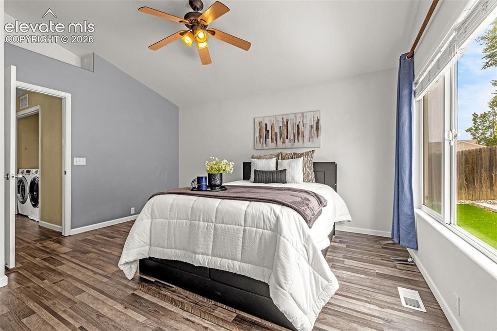 Image 16 of 49: Main level master with vaulted ceiling with a ceiling fan and light fixture