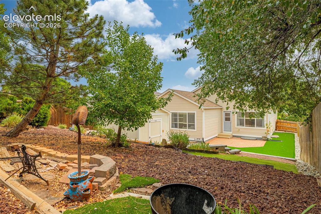 Image 30 of 49: Expansive backyard featuring a rock ground covering, mature trees, and a wo