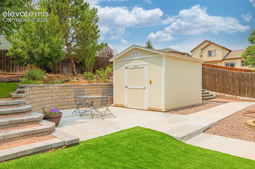 Image 32 of 49: Expansive outdoor area featuring a brick paver patio, artificial turf lawn,