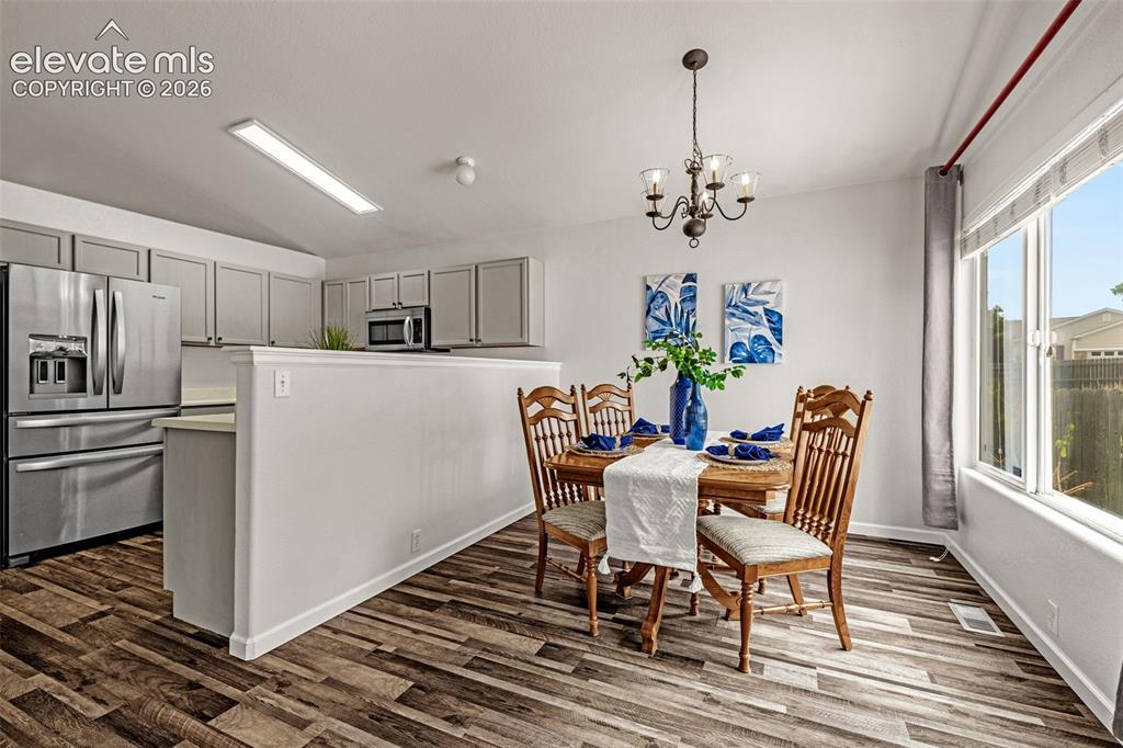 Image 9 of 49: Dining area with wood-finish flooring, a multi-pane window, and an overhead