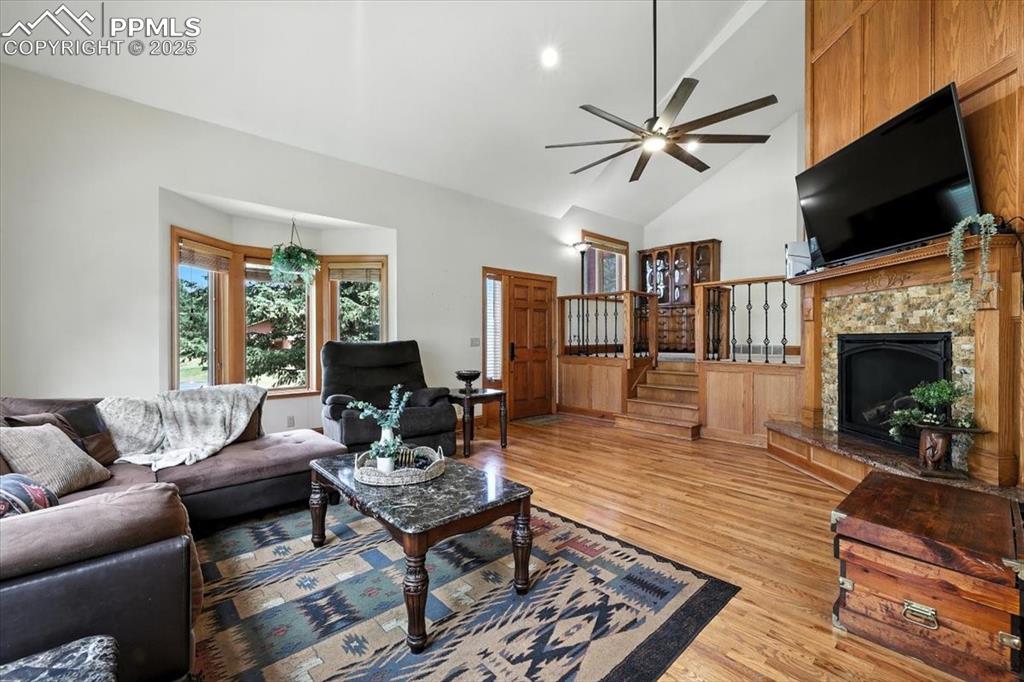 Image 11 of 36: Living area featuring light wood-type flooring, ceiling fan, stairs, a fire