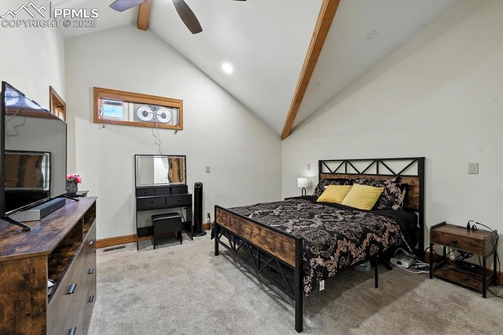 Image 19 of 36: Bedroom featuring light carpet, high vaulted ceiling, beamed ceiling, and a
