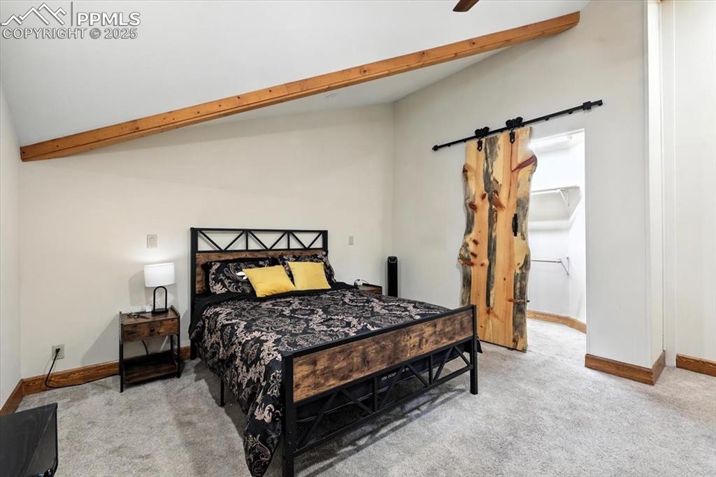 Image 20 of 36: Bedroom with light colored carpet, a barn door, and a ceiling fan