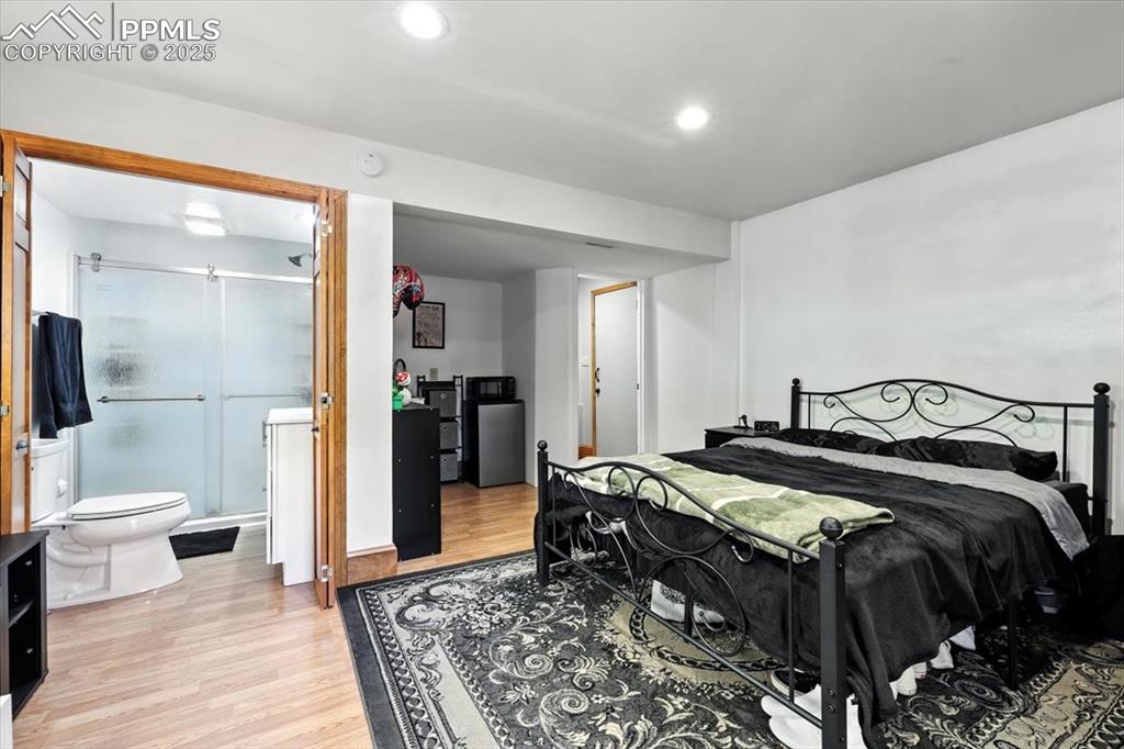 Image 25 of 36: Bedroom featuring light wood-style floors, recessed lighting, and ensuite b