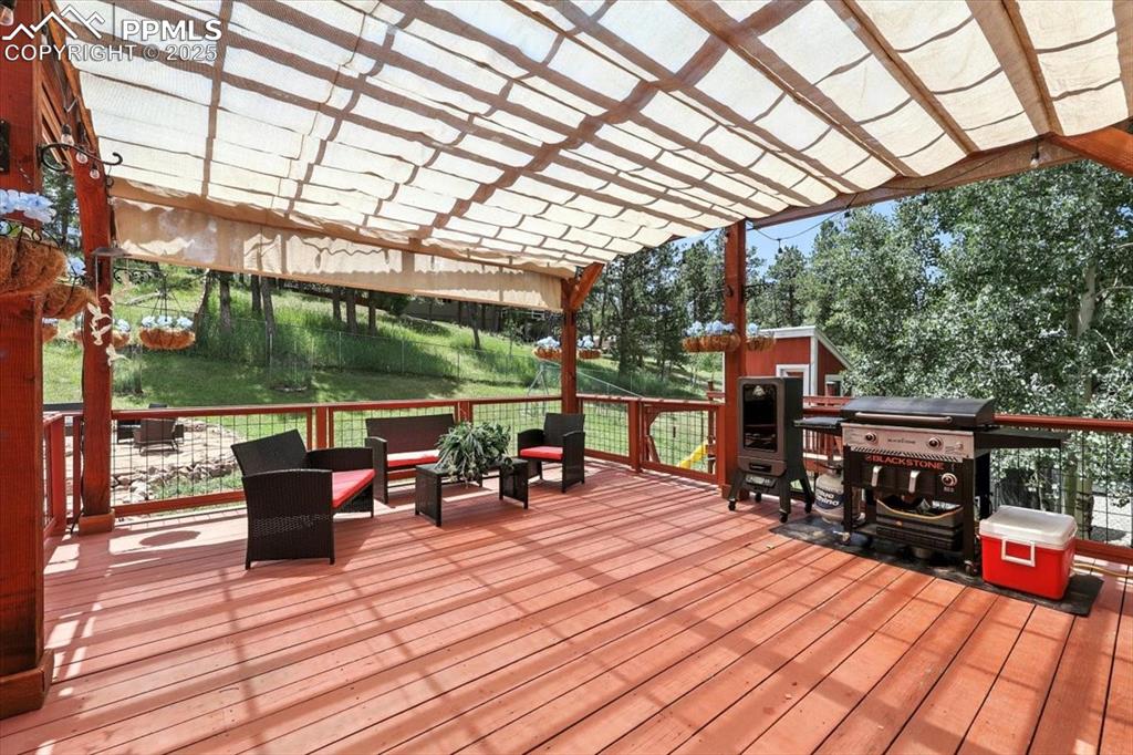 Image 28 of 36: Wooden deck featuring a pergola, a grill, and an outdoor structure