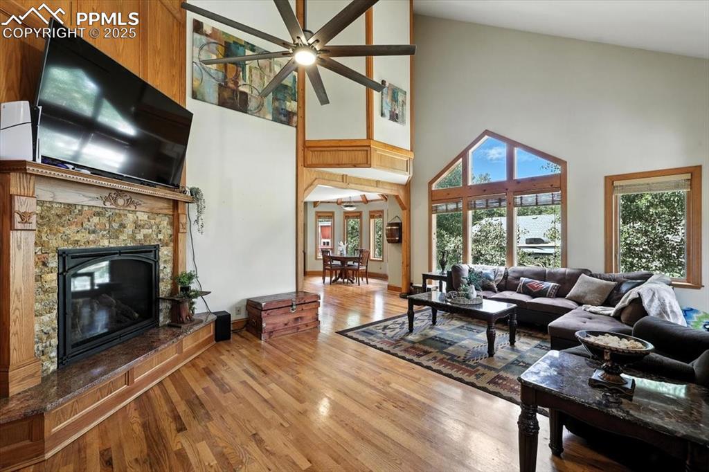 Image 3 of 36: Living area with high vaulted ceiling, ceiling fan, a fireplace, and wood f