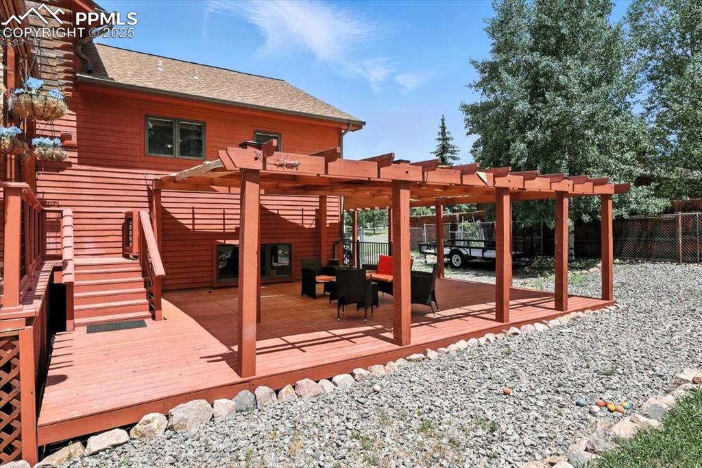 Image 31 of 36: Wooden deck with a fenced backyard and a pergola