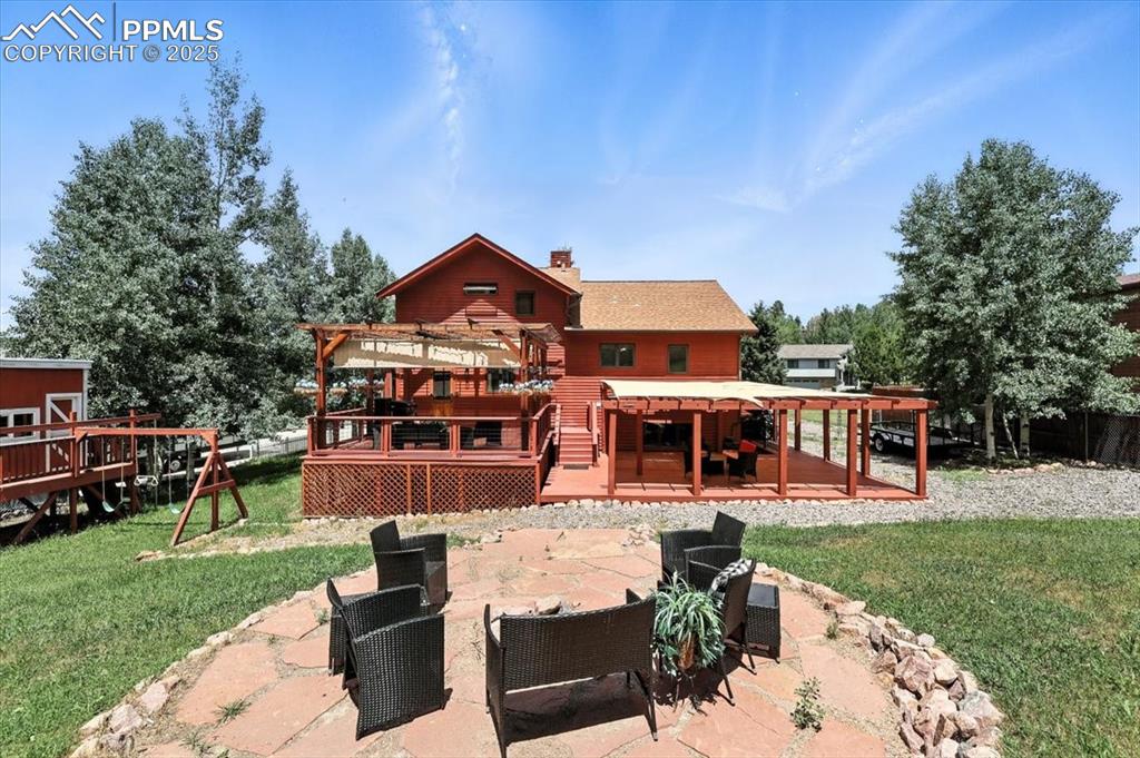 Image 33 of 36: Rear view of house featuring a patio area, a deck, a pergola, a chimney, an