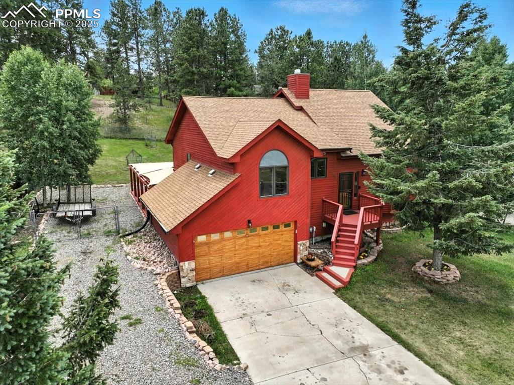 Image 34 of 36: Rustic home featuring roof with shingles, concrete driveway, an attached ga