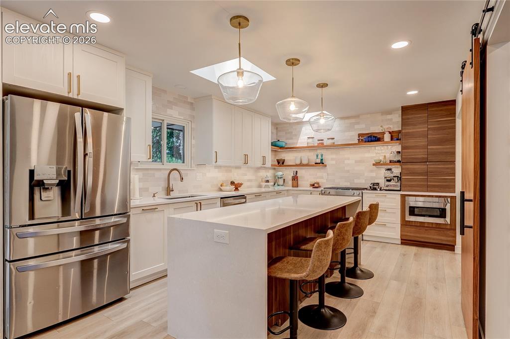 Image 10 of 50: Modern kitchen featuring white shaker cabinetry, stainless steel appliances